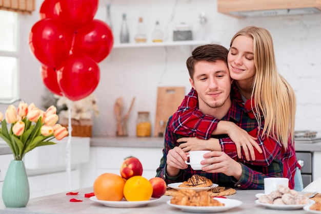 Donna del colpo medio che abbraccia uomo nella cucina