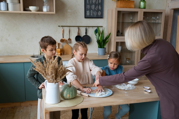 Donna del colpo medio che aiuta i bambini a cucinare