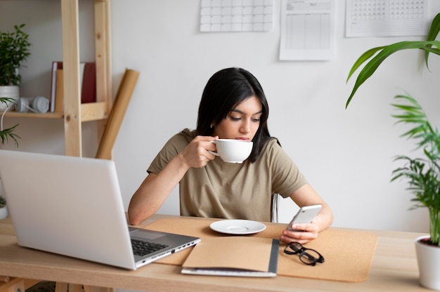 Donna del colpo medio che beve dalla tazza