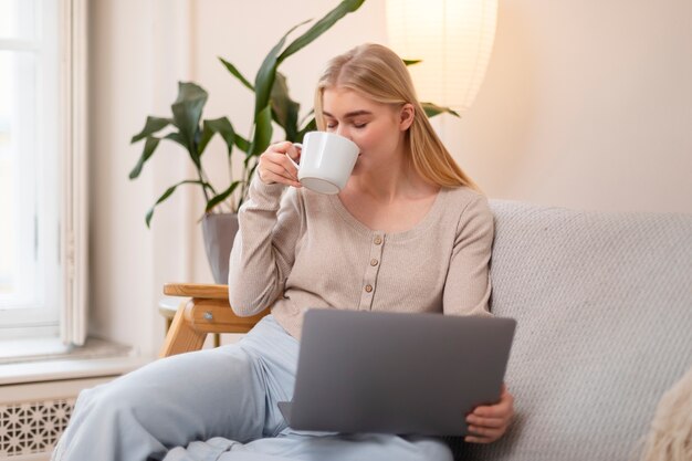 Donna del colpo medio che beve dalla tazza