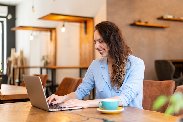 Donna del colpo medio che digita sul computer portatile