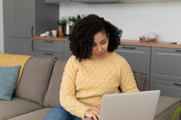 Donna del colpo medio che digita sul computer portatile