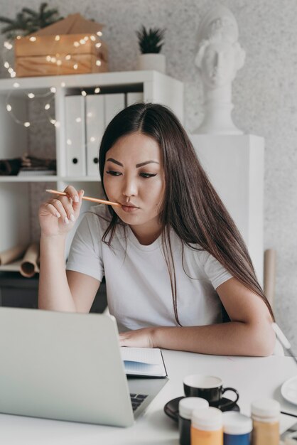 Donna del colpo medio che esamina il computer portatile