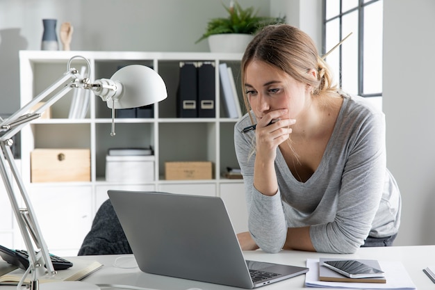 Donna del colpo medio che esamina il computer portatile