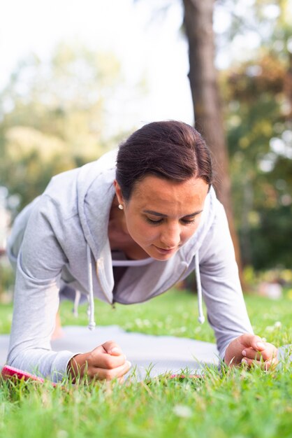 Donna del colpo medio che fa le plance all'aperto