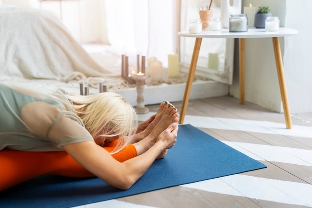 Donna del colpo medio che fa yoga al chiuso