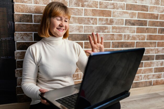 Donna del colpo medio che fluttua al computer portatile