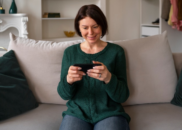 Donna del colpo medio che gioca con il suo telefono