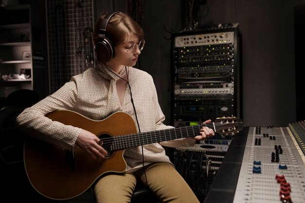 Donna del colpo medio che gioca la chitarra in studio