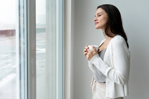 Donna del colpo medio che guarda fuori dalla finestra