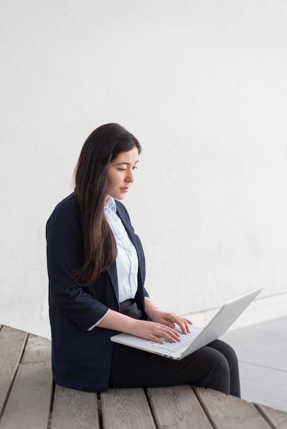 Donna del colpo medio che lavora al computer portatile