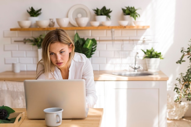 Donna del colpo medio che lavora al computer portatile