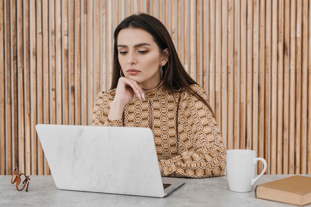 Donna del colpo medio che lavora al computer portatile