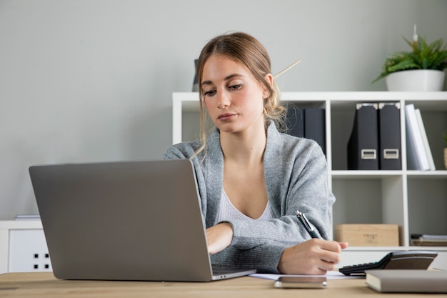 Donna del colpo medio che lavora al computer portatile