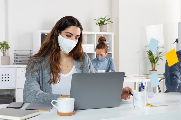 Donna del colpo medio che lavora al computer portatile