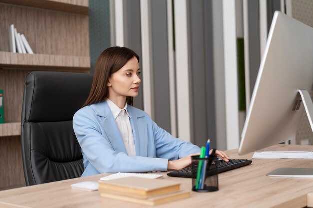 Donna del colpo medio che lavora con il computer