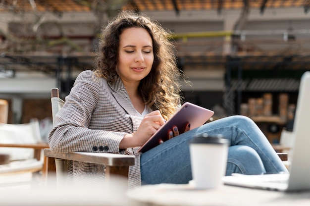 Donna del colpo medio che lavora con il tablet