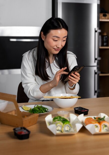 Donna del colpo medio che mangia alimento asiatico