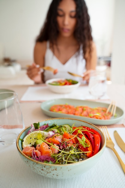 Donna del colpo medio che mangia ciotola di salmone