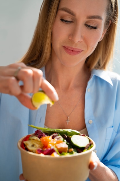 Donna del colpo medio che mangia ciotola di salmone