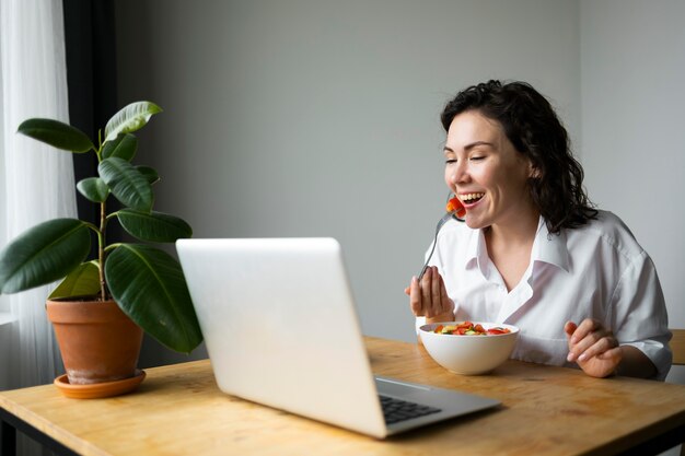 Donna del colpo medio che mangia insalata