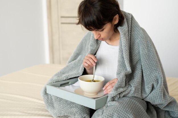 Donna del colpo medio che mangia la zuppa