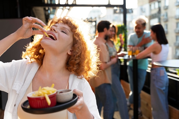 Donna del colpo medio che mangia patatine fritte