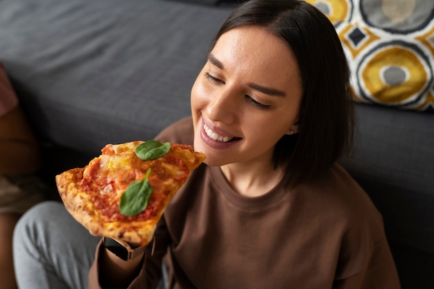 Donna del colpo medio che mangia pizza deliziosa