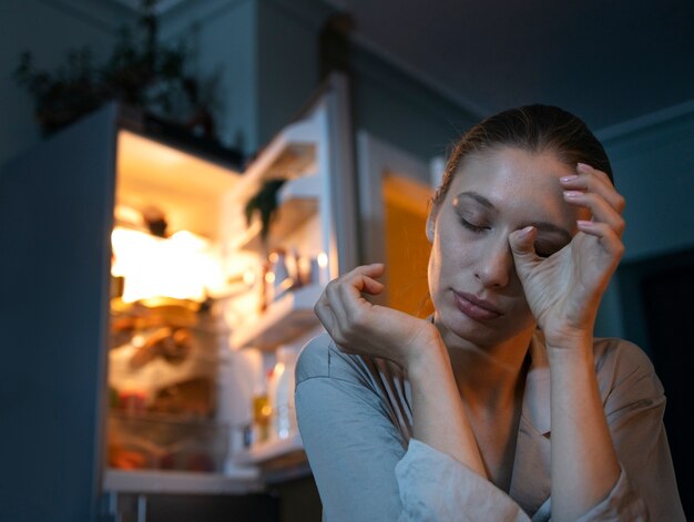 Donna del colpo medio che mangia spuntini di notte