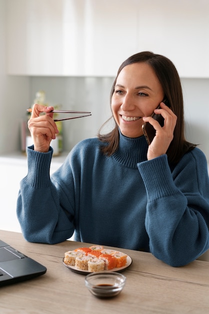 Donna del colpo medio che mangia sushi a casa