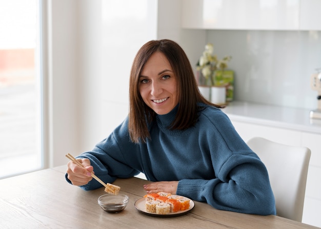 Donna del colpo medio che mangia sushi a casa