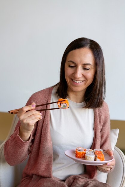 Donna del colpo medio che mangia sushi a casa