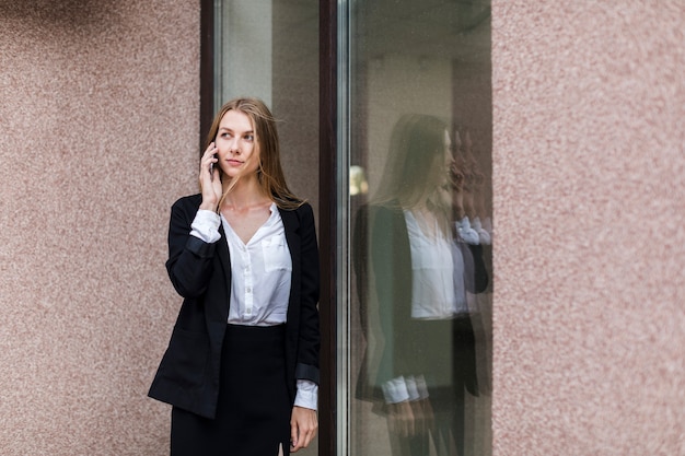 Donna del colpo medio che parla sul telefono dalla finestra