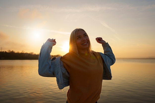 Donna del colpo medio che posa al tramonto