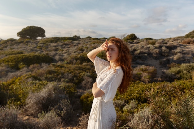 Donna del colpo medio che posa in vestito bianco