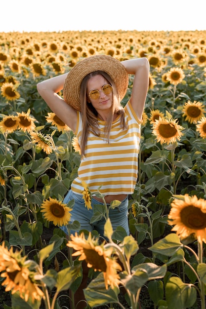 Donna del colpo medio che posa nel campo di girasole