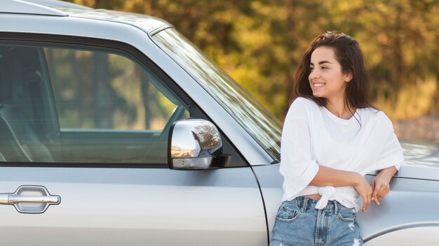 Donna del colpo medio che posa vicino all'automobile