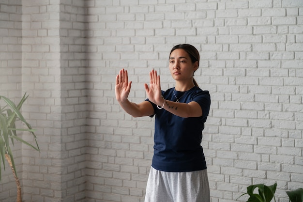 Donna del colpo medio che pratica il tai chi al chiuso