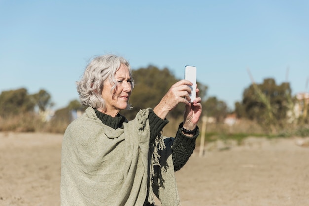 Donna del colpo medio che prende le foto all'aperto