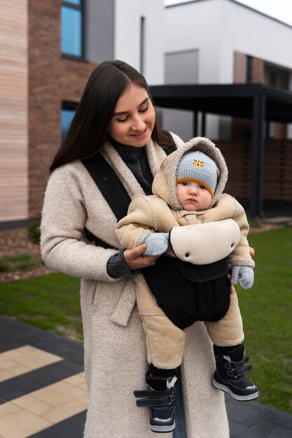 Donna del colpo medio che tiene bambino in marsupio