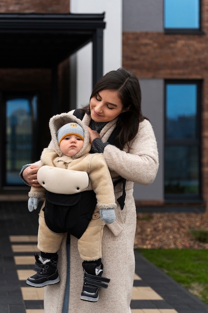 Donna del colpo medio che tiene bambino in marsupio