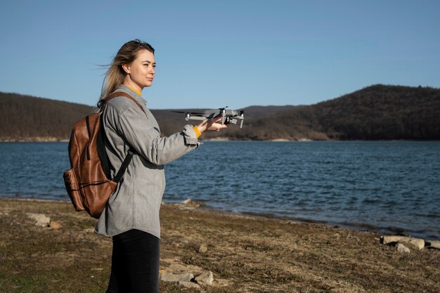 Donna del colpo medio che tiene drone all'aperto