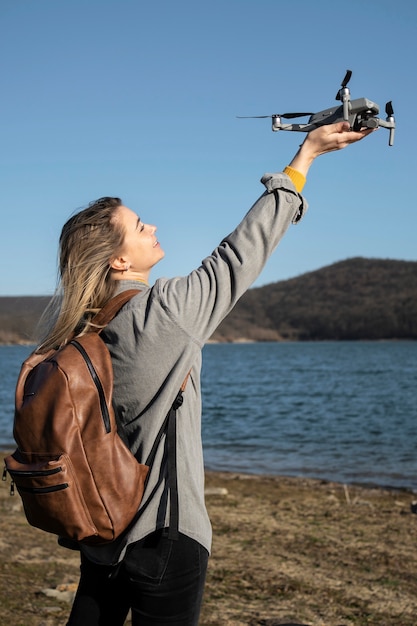 Donna del colpo medio che tiene il drone all'esterno