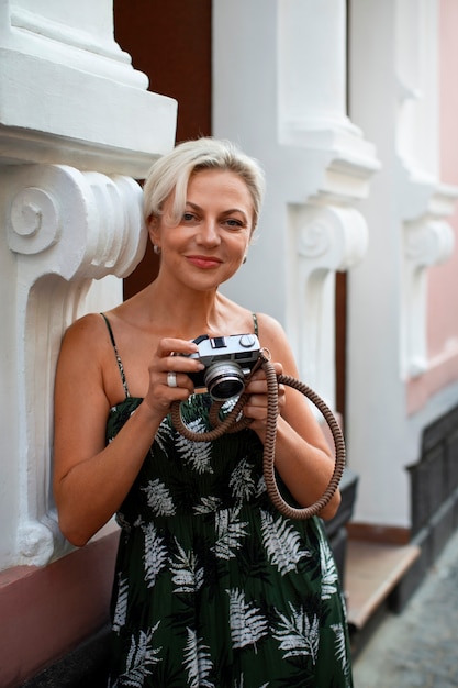 Donna del colpo medio che tiene la macchina fotografica