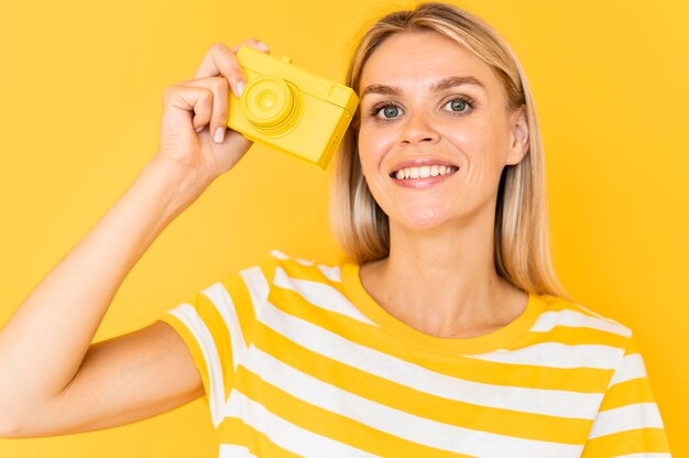 Donna del colpo medio che tiene macchina fotografica gialla