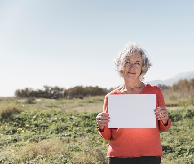 Donna del colpo medio che tiene un pezzo di carta