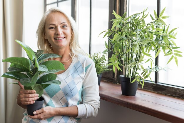 Donna del colpo medio che tiene una pianta