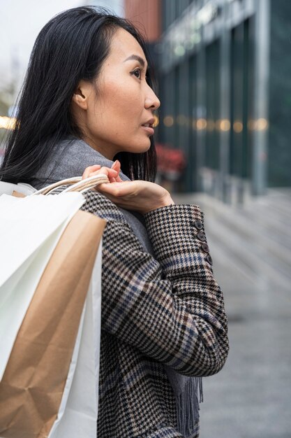 Donna del colpo medio che trasporta le borse della spesa