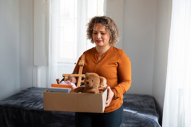 Donna del colpo medio che trasporta scatola con le merci