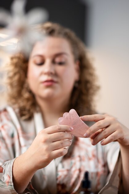 Donna del colpo medio che usa lo strumento gua sha